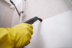 gloved hand steam cleaning grout