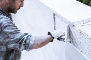 Image of a man applying thinset to a wall. 
